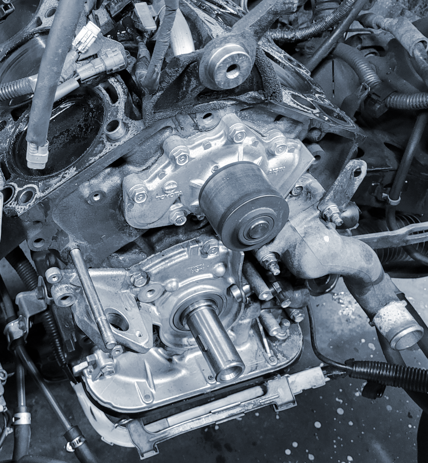 A partially dismantled view of a Toyota V-6 engine, showing water pump and oil pump after timing belt assemblies have been removed.