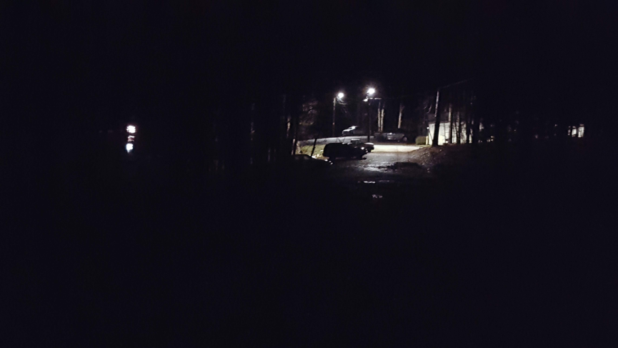 Parking lot lit by bright lights, surrounded by darkness.