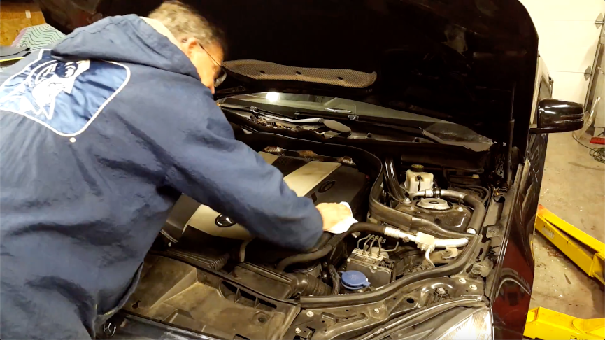 Putting an internal motor cover on a car engine.
