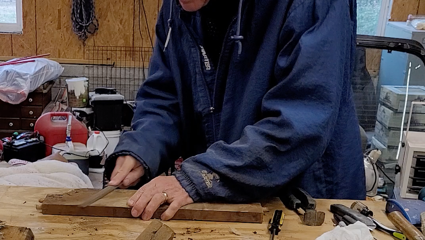 man filing nails smooth on an old chair part.