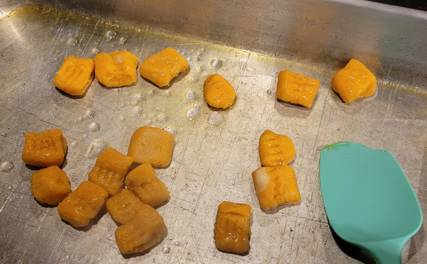 Gnocchi being collected in a cake pan after being boiled.