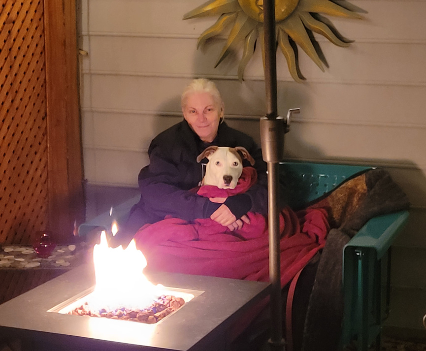 a woman and a dog by a fire.