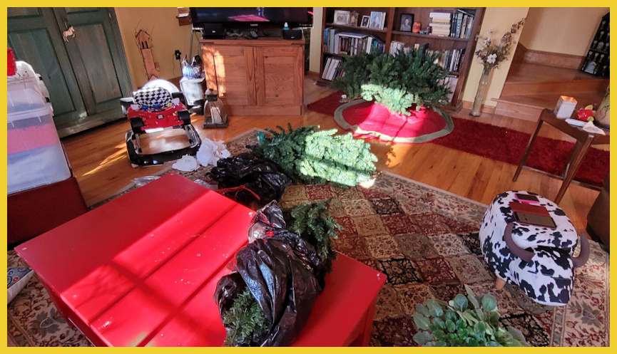 A messy family room with half-put-away Christmas decorations