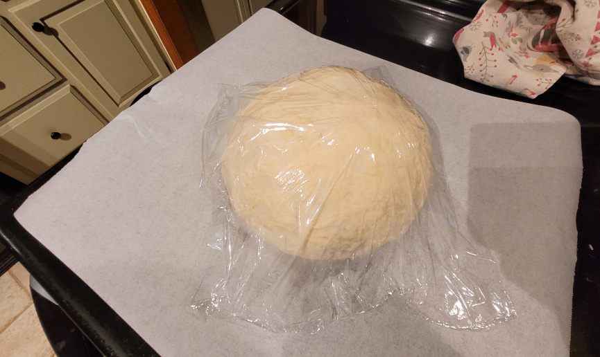 breadh dough rising under plastic wrap