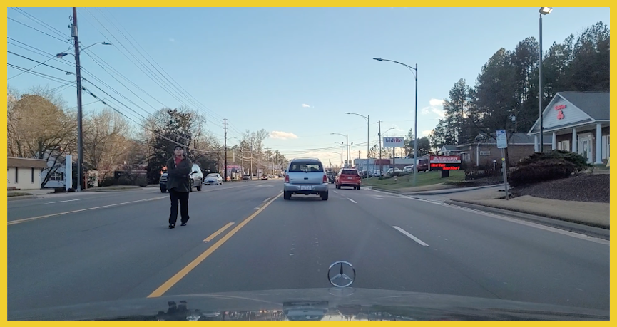 A woman walks in the middle lane on a busy city street