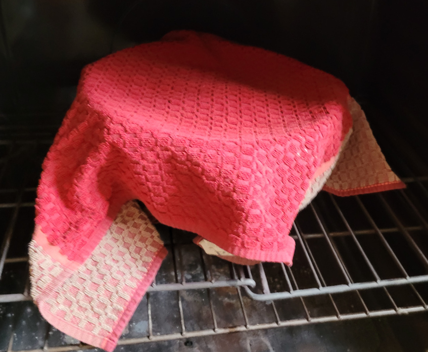 covered towel, bread in a bowl in a warm oven